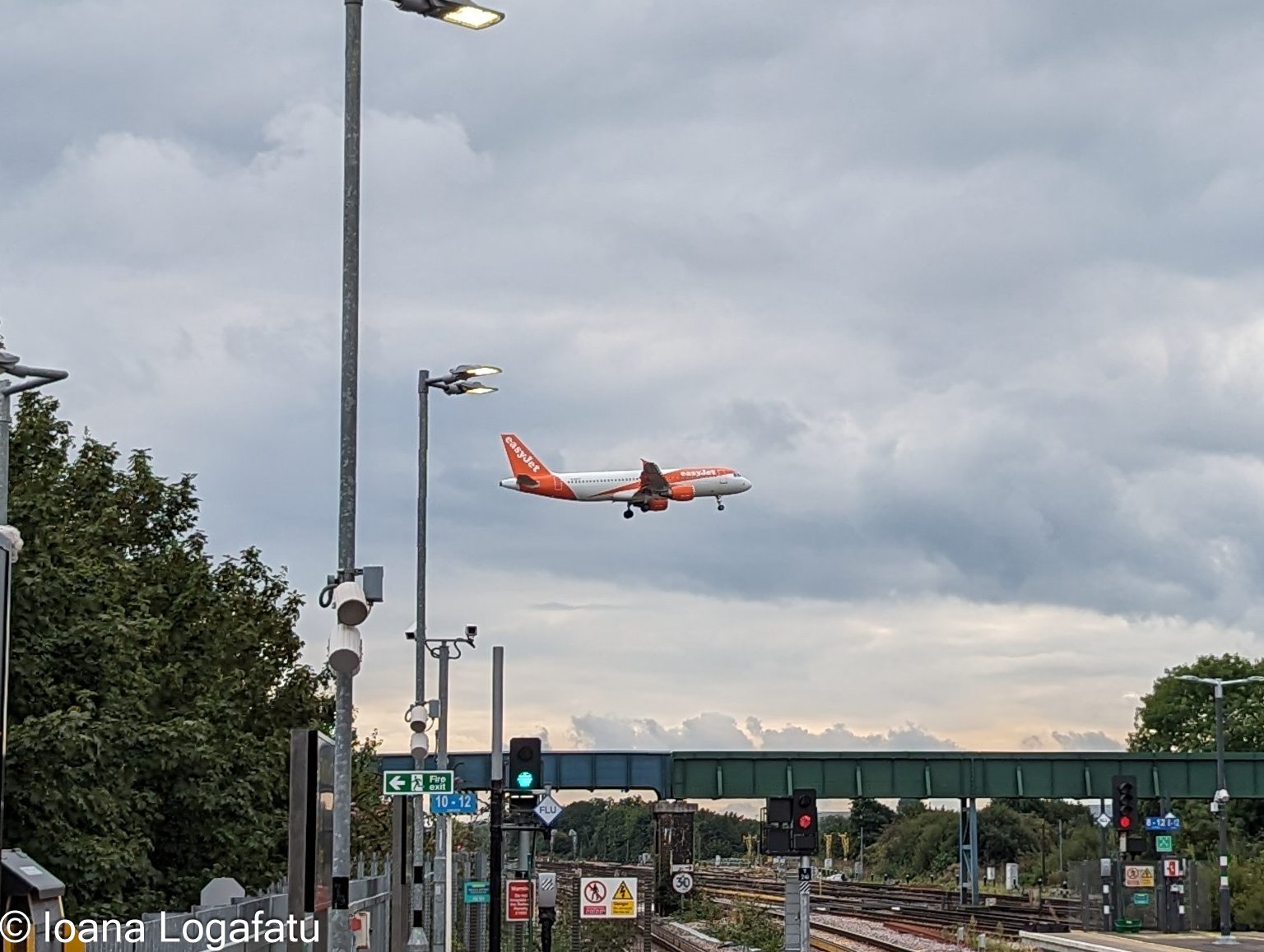 Plane soars over train station clouds